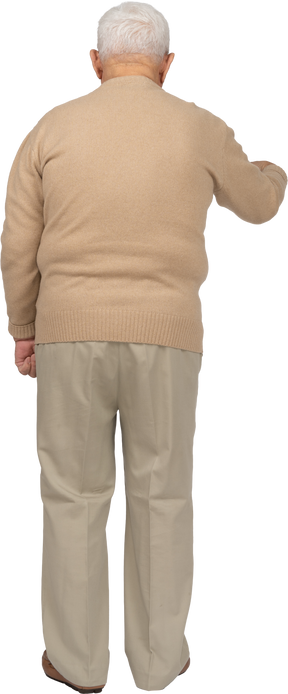 Rear view of an old man in casual clothes pointing down