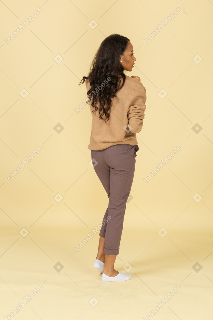Vista traseira de uma jovem mulher de pele escura tocando seu ombro