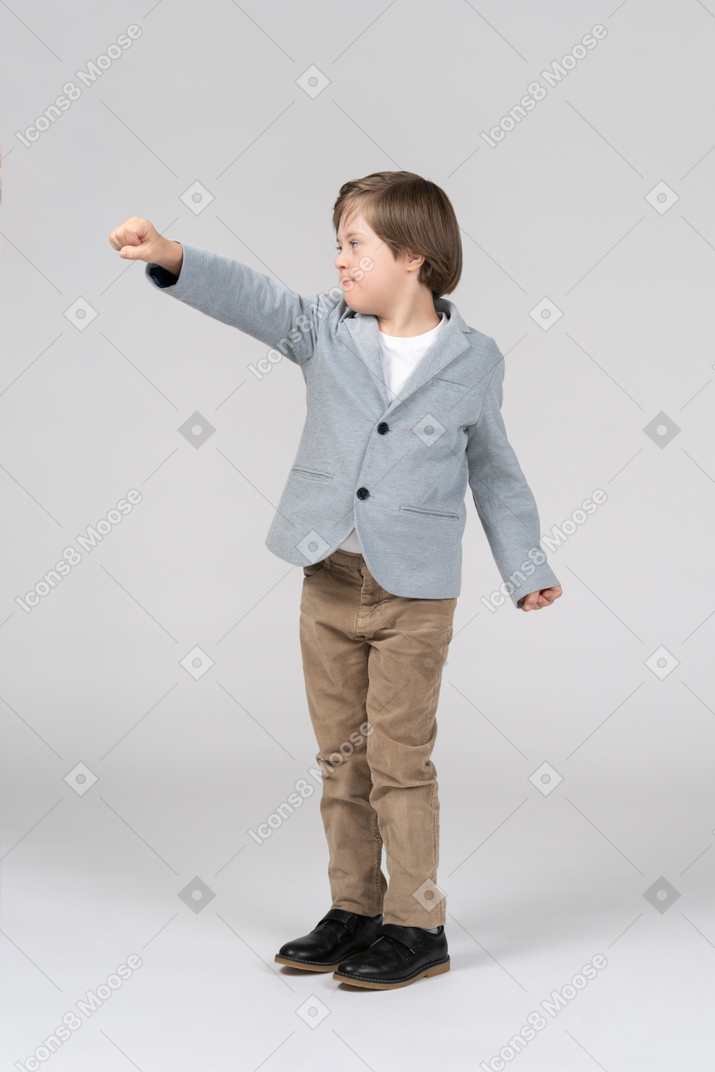 Little boy in suit reaching his fist forward