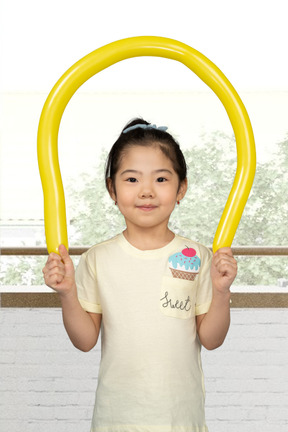 Cute asian girl playing with a yellow balloon