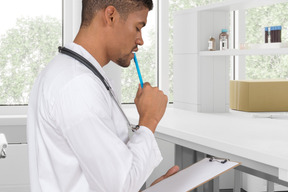 A man holding a clipboard and a pencil in his mouth