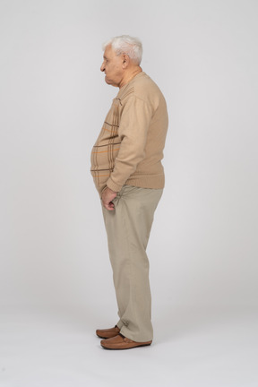 ポケットに手を入れて立っているカジュアルな服装の老人の側面図