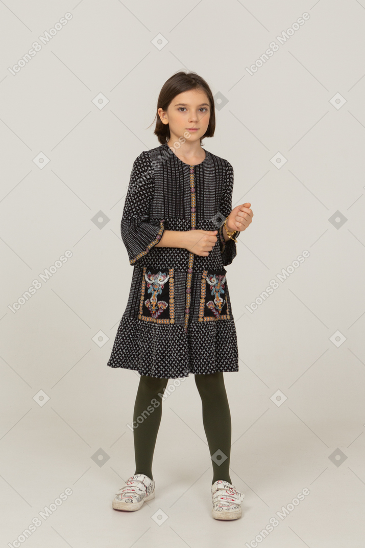 Front view of a gesticulating little girl in dress looking at camera