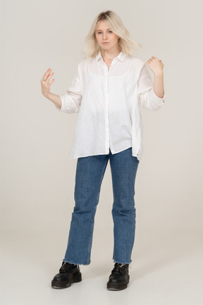 Front view of a blonde female touching her messy hair and looking at camera