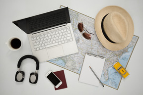 Laptop, headphones and other accessories arranged on a map