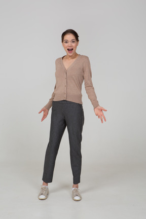 Front view of a pleased young lady in beige pullover outspreading her hands