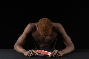 Front view of a withdrawn young afro man sitting near meat