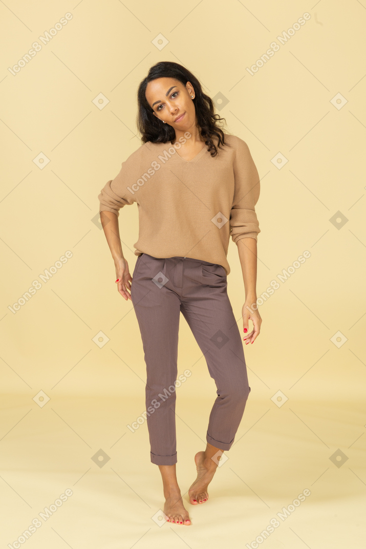 Front view of a dark-skinned female in casual clothes putting hand on hip