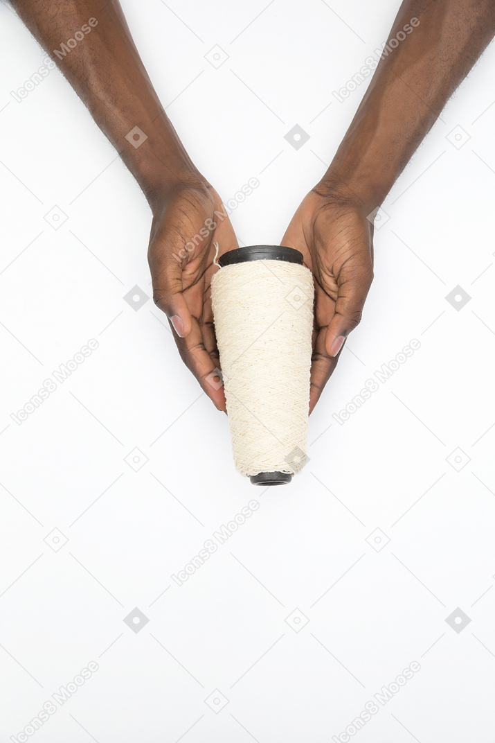 Black male hands holding a reel of threads