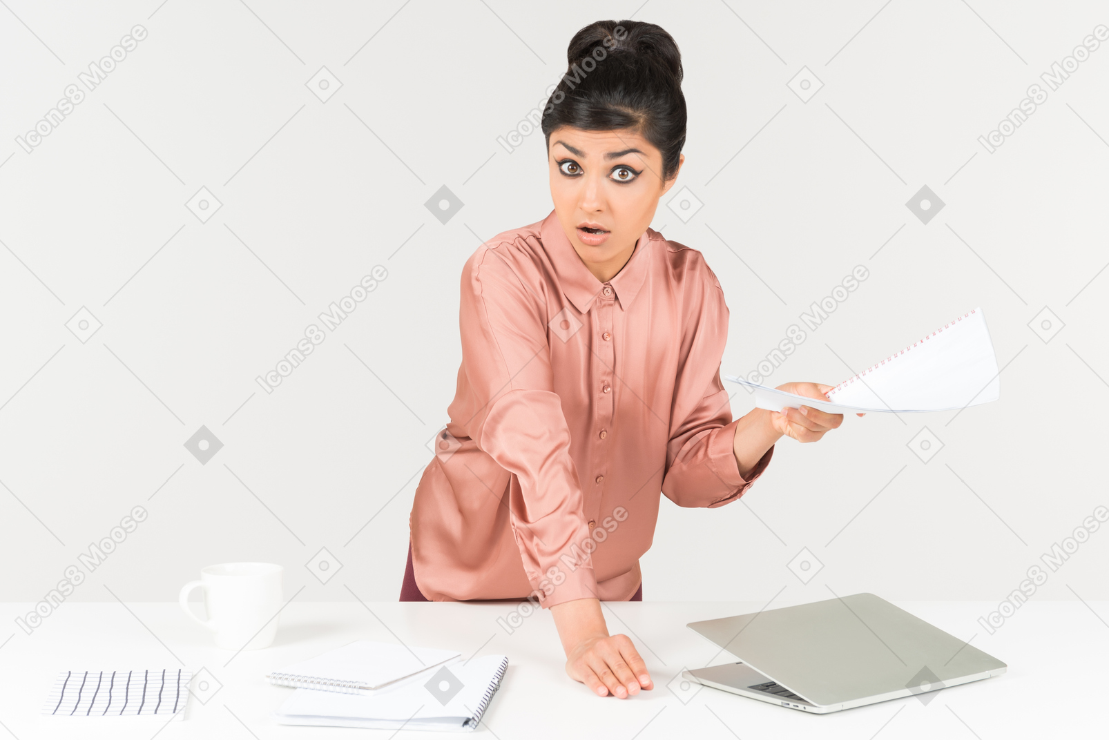 Stunned young indian office worker standing at the office desk and holding papers