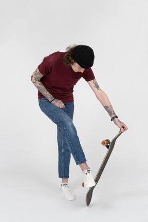 A teenager looking at his skateboard