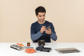 A young man in casual blue clothes working with computer details