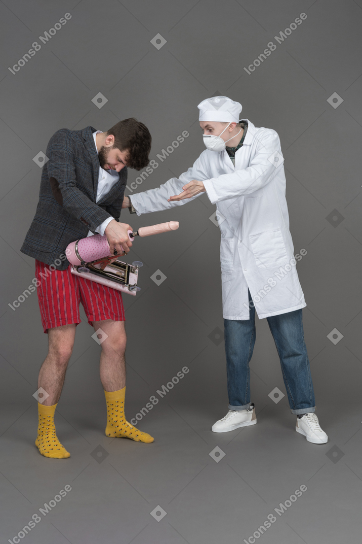 Young man holding sex machine while doctor observing