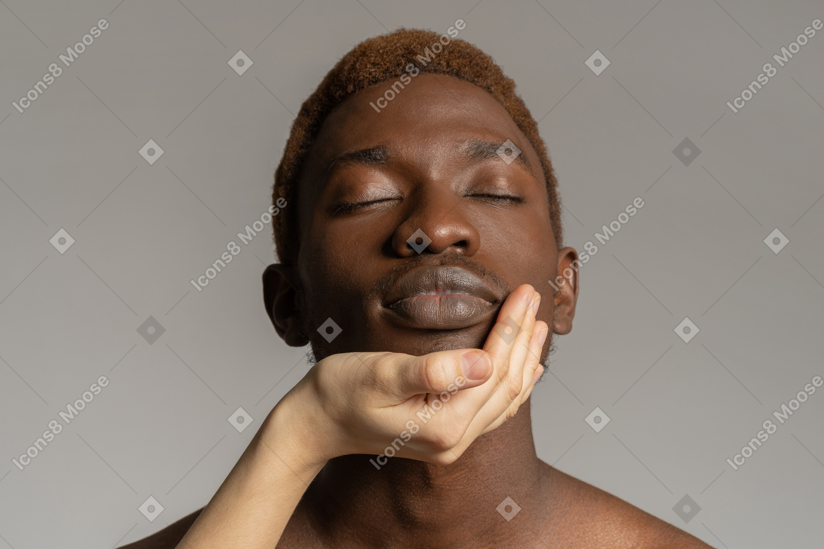 Mão branca tocando o rosto de um jovem negro