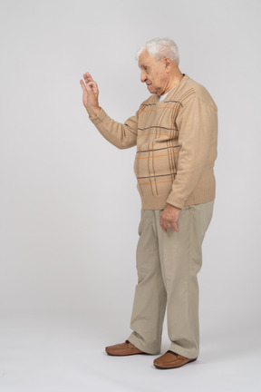 Вид сбоку на старика в повседневной одежде, показывающего жест "ок"