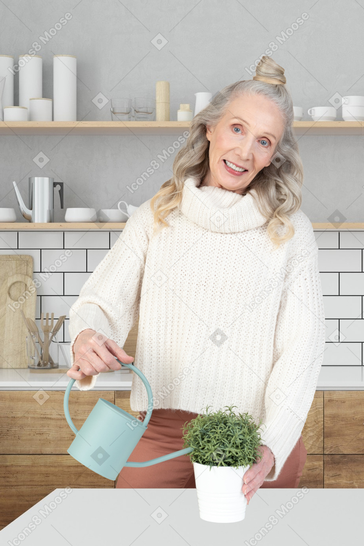 A woman holding a watering can and a potted plant