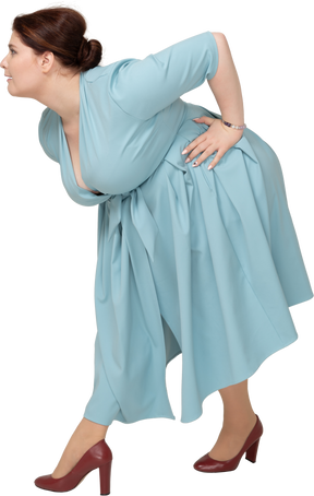 Vista lateral de uma mulher de vestido azul curvando-se