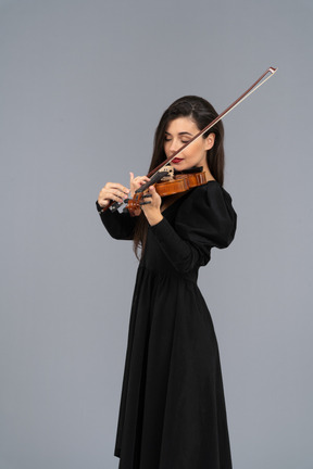 Close-up de uma jovem de vestido preto tocando violino