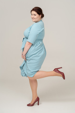 Side view of a woman in blue dress posing on one leg