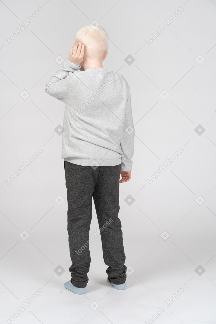 Back view of a boy putting palm to his ear