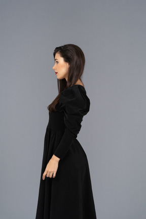 Vista lateral de uma jovem em um vestido preto parada