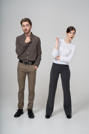 Front view of a curious young couple in office clothing