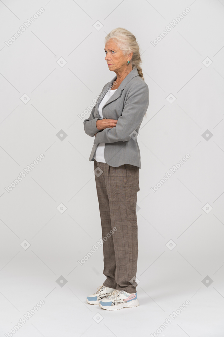 一位身穿西装、双臂交叉站立的老妇人的侧视图