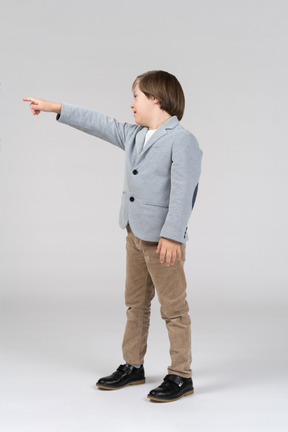 Side view of a little boy standing and pointing to the left