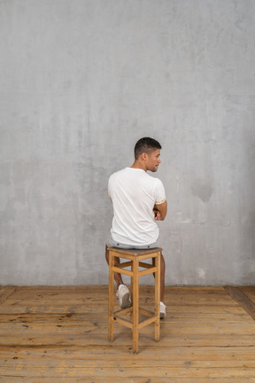 Rear view of young man sitting and looking aside