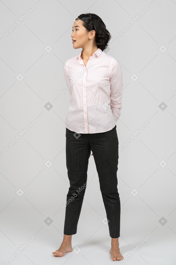 Distracted woman in office clothes with hands behind back