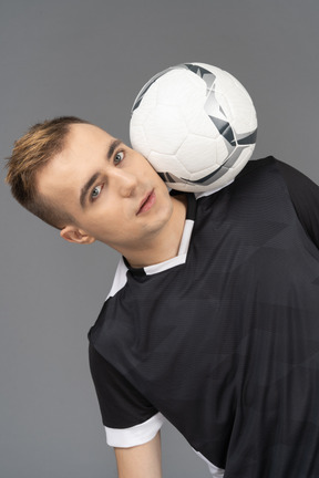 Young man balancing a soccer ball on his shoulder