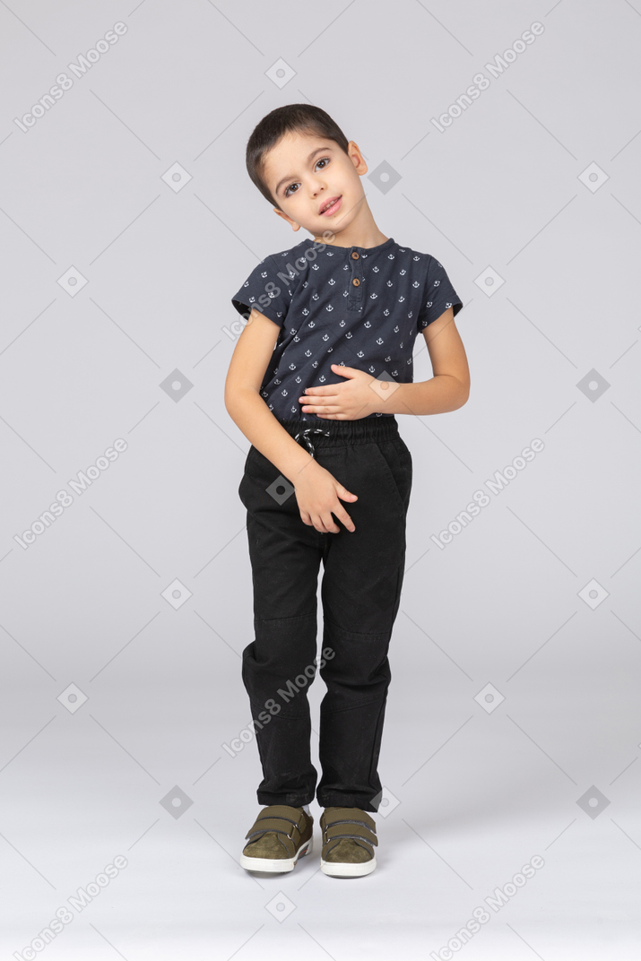 Front view of a cute boy posing with hand on stomach and looking at camera