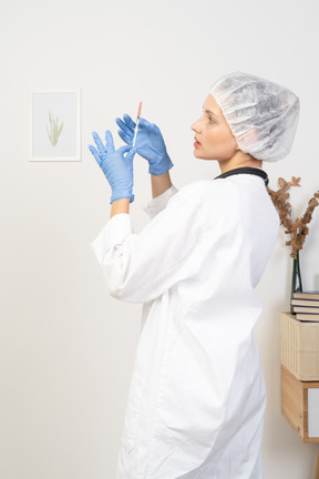 Vista posteriore di una giovane dottoressa che tiene in mano una siringa