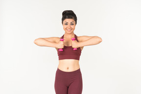 Young indian woman in sportswear holding hand weights