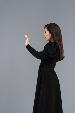 Side view of a young lady in a black dress raising her hand