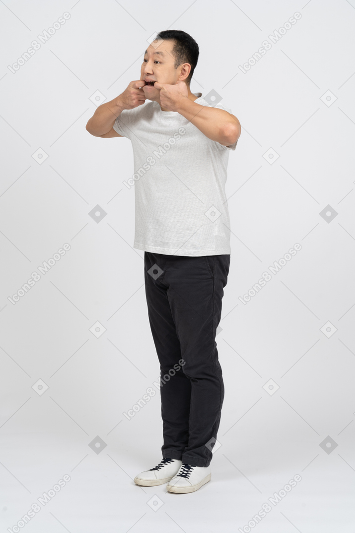 Man in casual clothes opening mouth with fingers