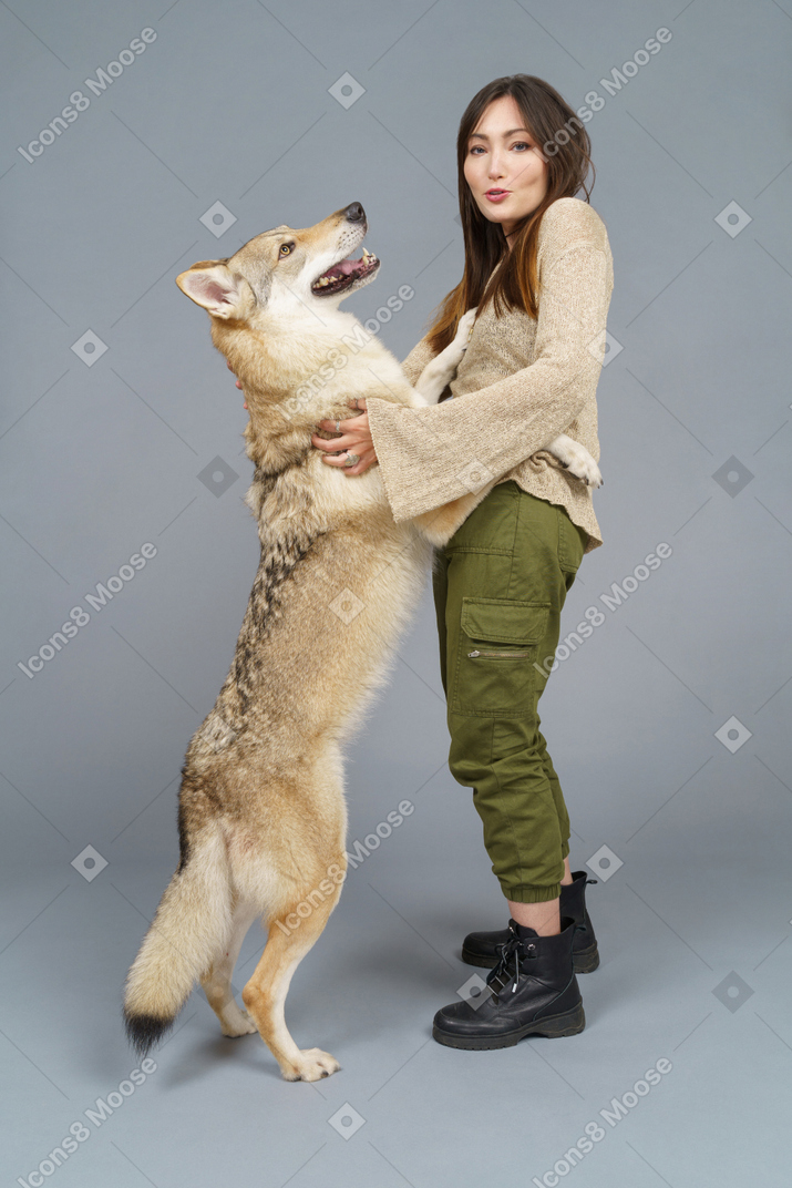 Vista lateral de una maestra abrazando a su perro
