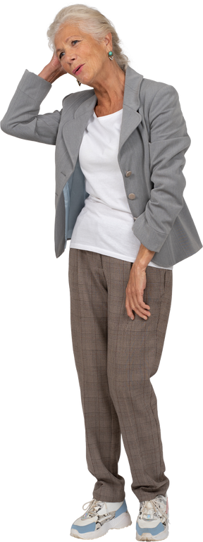 頭の後ろに手で立っているスーツを着た幸せな老婦人の正面図