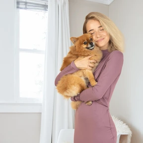 A woman holding a small dog in her arms