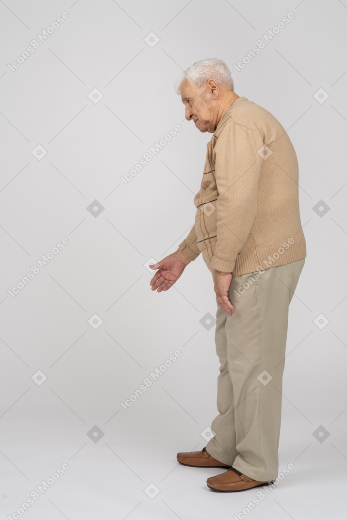 一位穿着休闲服的老人伸出手臂站立的侧视图