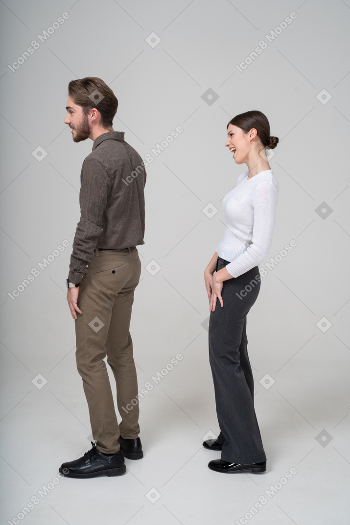 Vista lateral de una joven pareja riendo en ropa de oficina