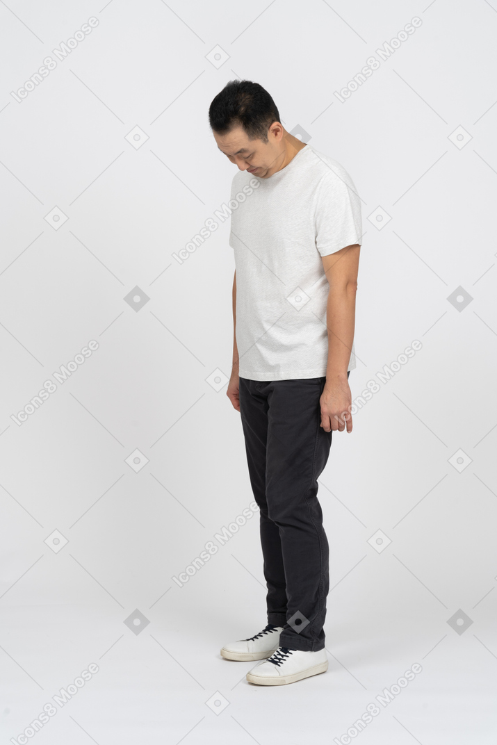 Homem com roupas casuais em pé com a cabeça abaixada