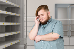 Man standing in a supermarket with empty shelves