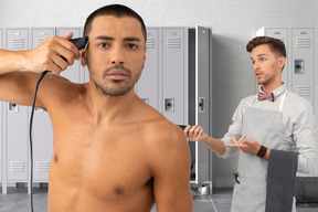 Man shaving his head with electric razor and another man looking at him