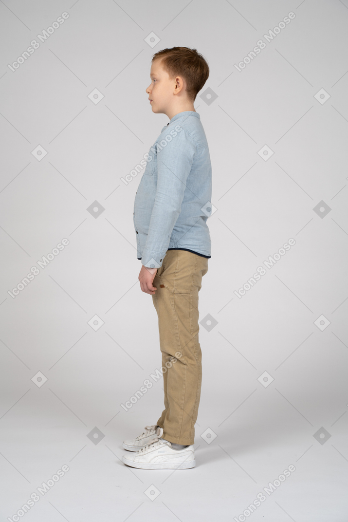 Cute boy in casual clothes standing in profile