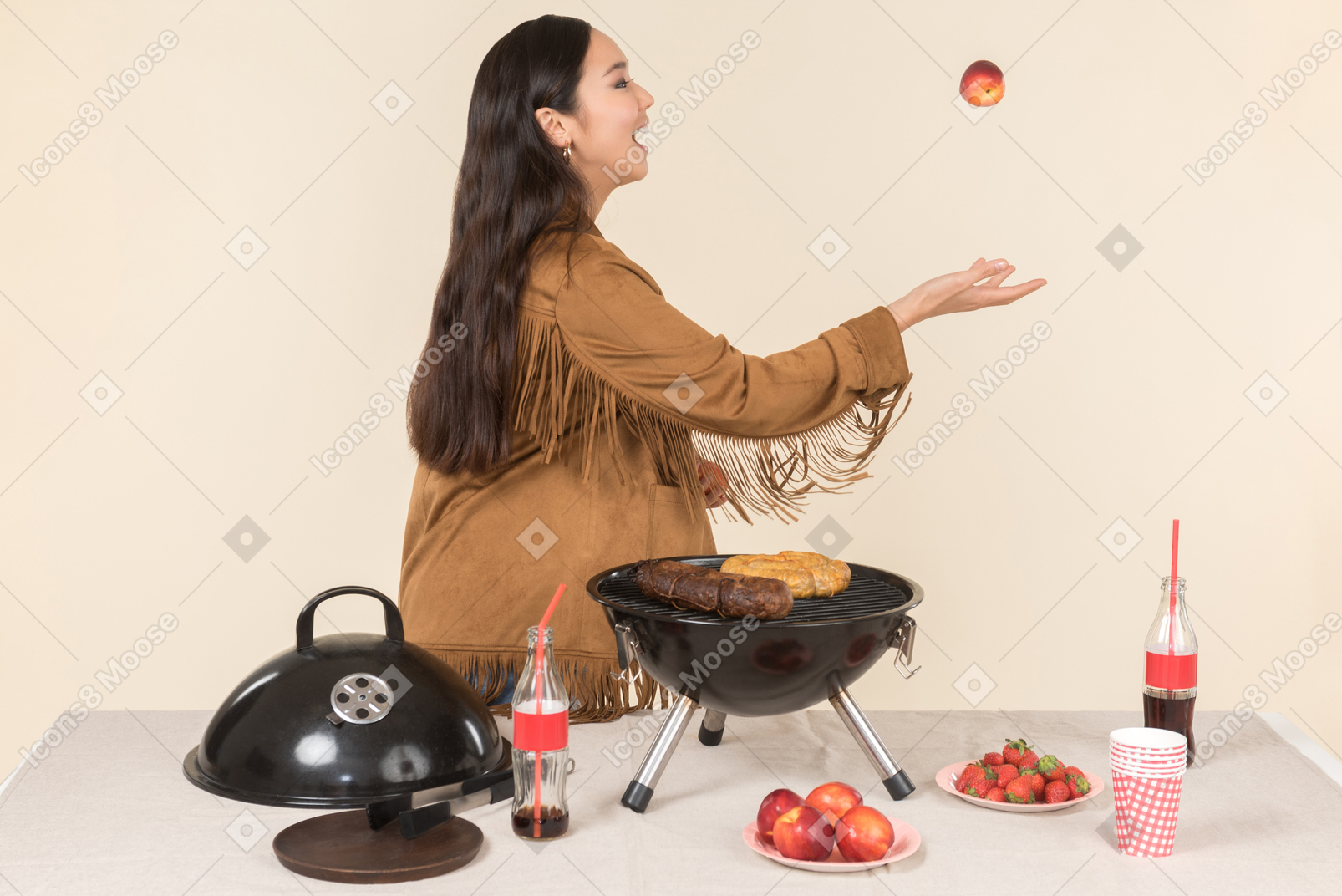 Young asian woman standing near grill and throwing a fruit