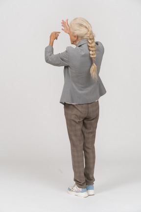 Rear view of an old lady in suit pointing with fingers