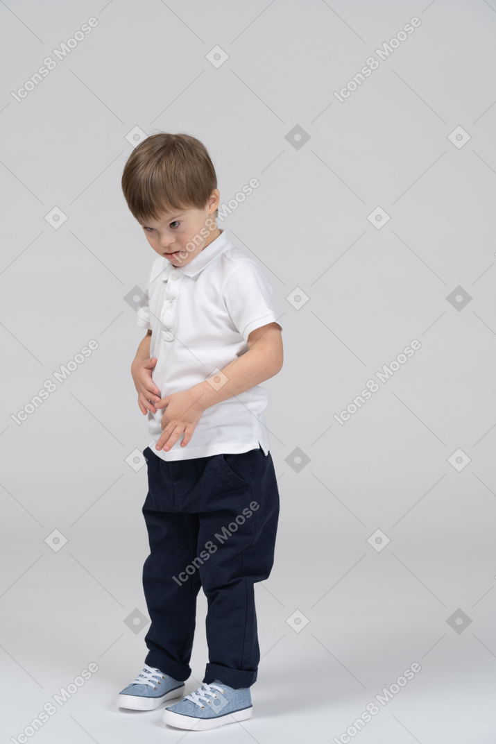 Little boy standing with his hands on his stomach