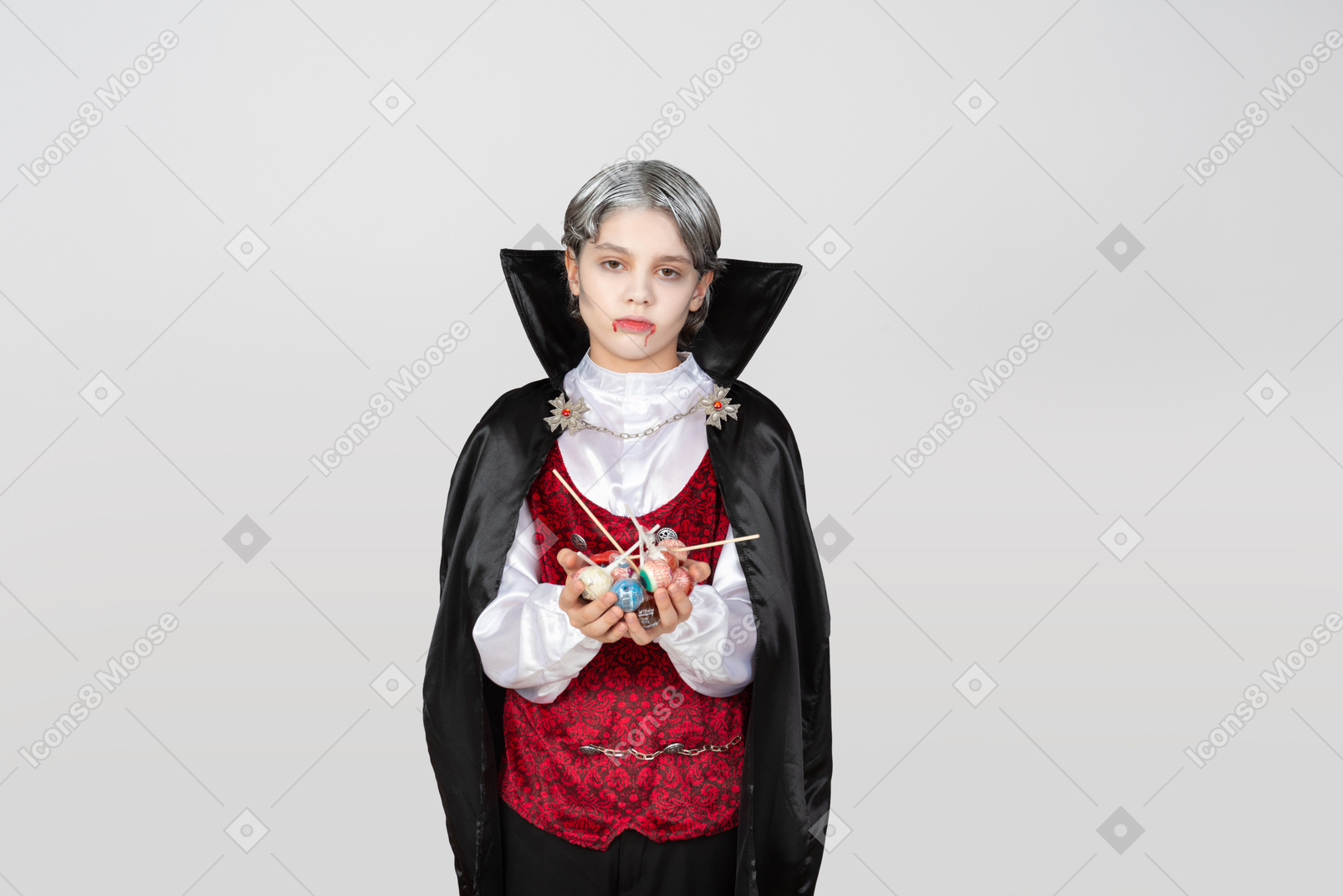 Boy in vampire costume holding candies