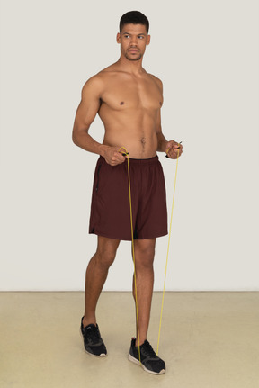 Bare chested young man in sport shorts standing on the jumping rope